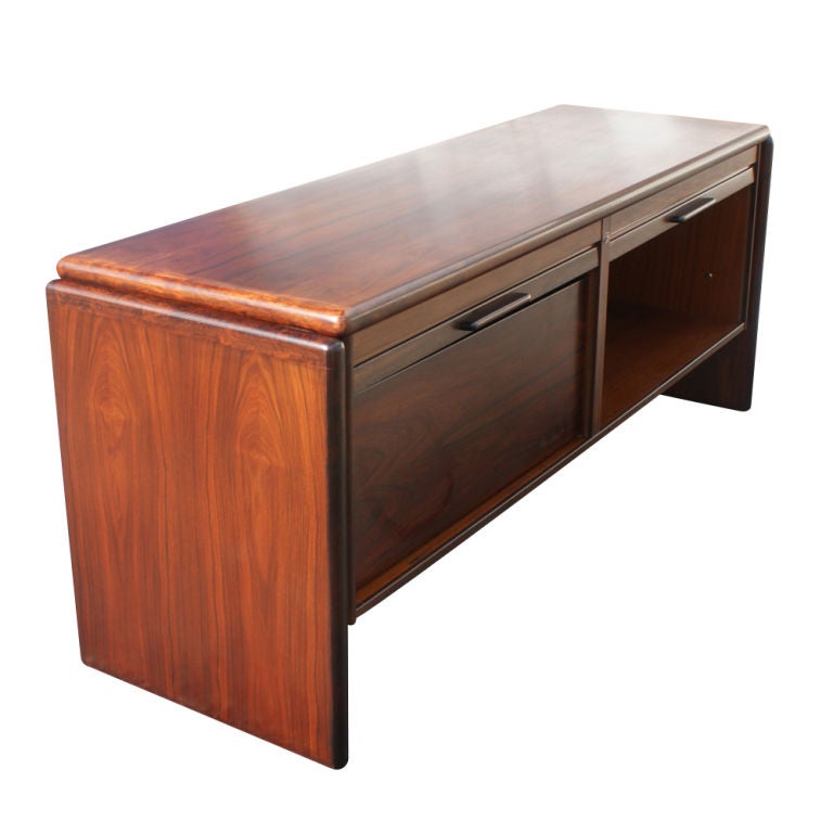 A mid century modern rosewood credenza made in Denmark by Dyrlund.  Two tambour doors, one concealing a double file drawer.  The back is finished.  As shown in the last image, we also have a matching desk available on 1stdibs.