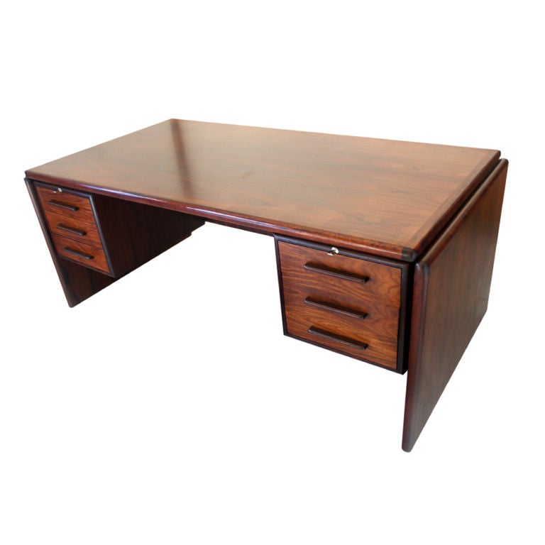 A mid century modern rosewood desk made by Dyrlund in Denmark.  Six locking drawers with oanel legs.  As shown in the last image, we also have a matching credenza available on 1stdibs.