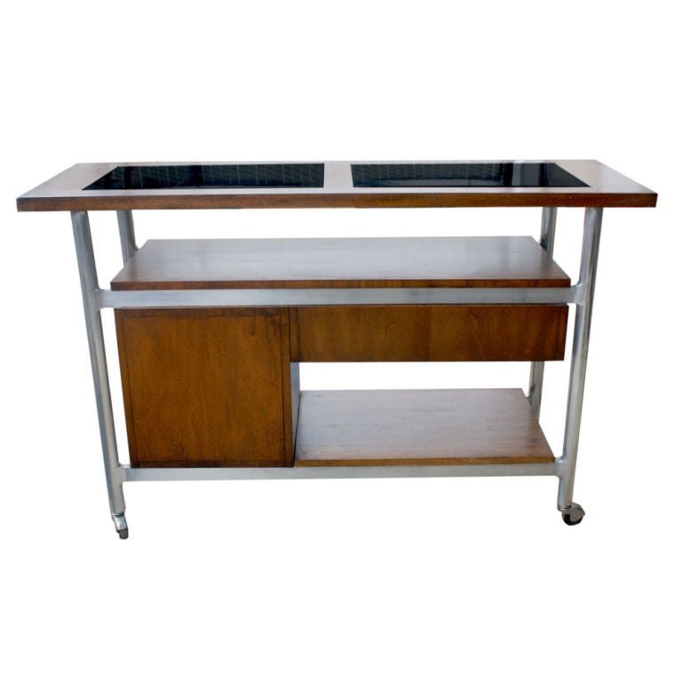 A mid century modern rolling bar cart.  A chrome frame on casters with burled veneer case.  Multiple shelf spaces, a drawer and door.