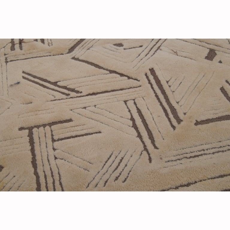 A large mid century modern rug designed and made by Edward Fields.  A beige background with brown geometric patterns.