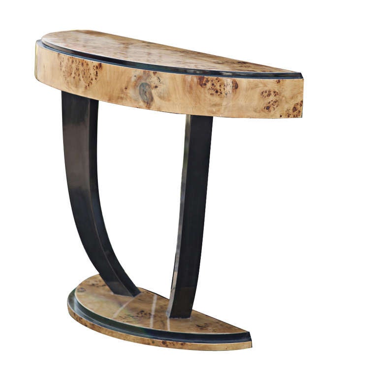 A lovely Art Deco style console or pier table featuring a semi-oval burledwood top and base supported by to two curvilinear ebonized supports.