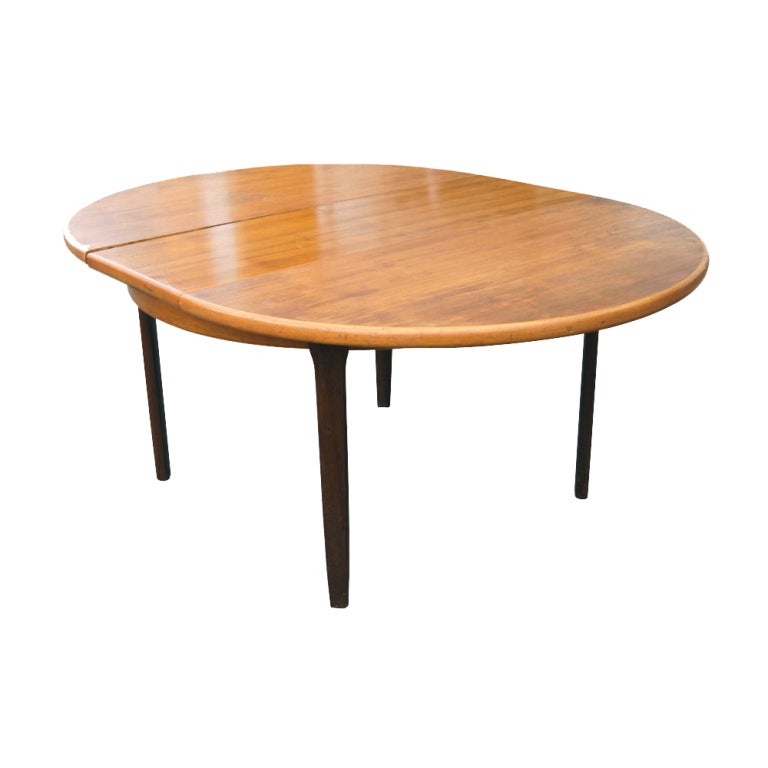 A mid century modern teak extension dining table made by J. L. Møller.  The self-storing butterfly leaf turns a 48