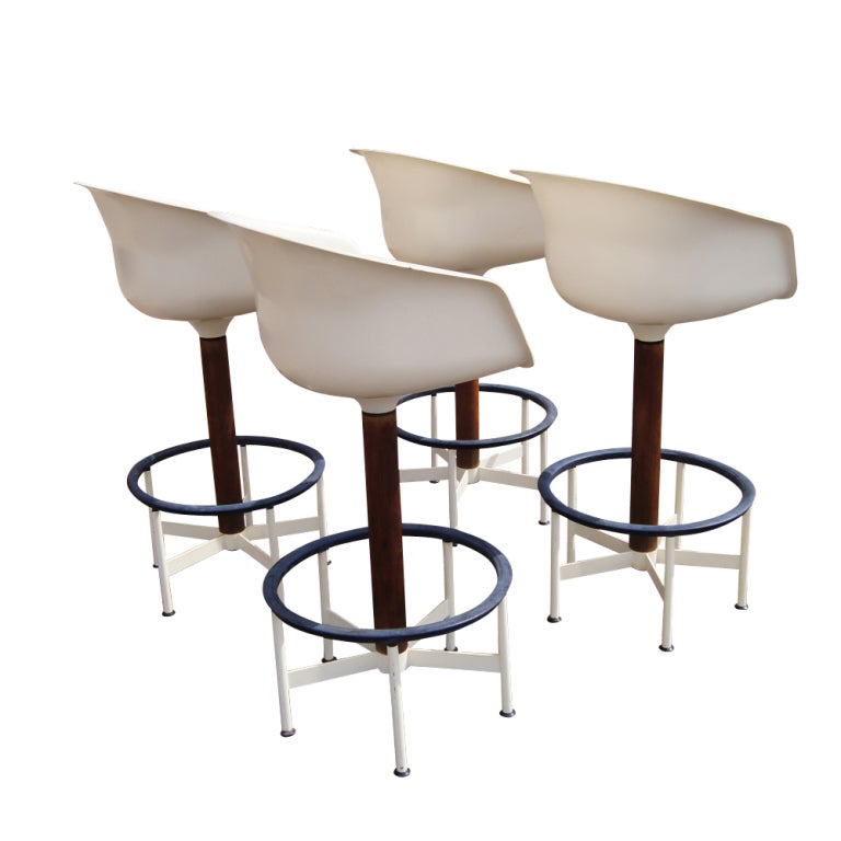 A set of four mid century modern bar stools in the manner of Eero Saarinen made by Burke.  Fiberglass shells with new leather cushions and cast metal bases.  The seat height is 30.75