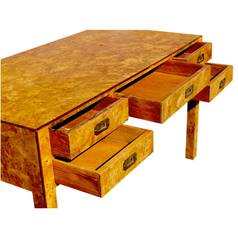 A writing desk in burled wood with five drawers with campaign style hardware.