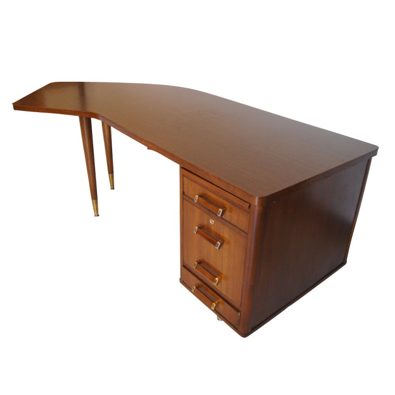 A mid century modern angled desk in walnut with a caned modesty screen in front and wood grain laminate top.  Three drawers including a pencil drawer and file drawer.  We also have a matching credenza listed on 1stdibs as shown in the last image.