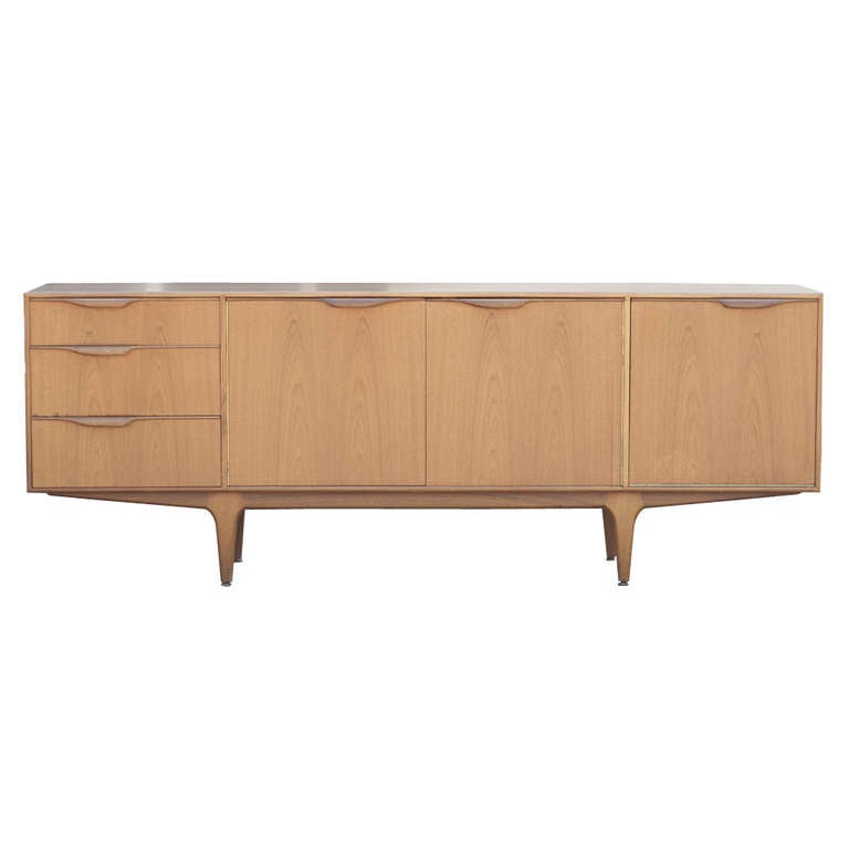 A simple and sleek mid century modern Scandinavian style buffet manufactured by A. H. McIntosh & Co. Ltd. in Scotland.  Made in a light colored walnut with a drop front bar and pull out drink mixing shelf.  There is plenty of storage with double