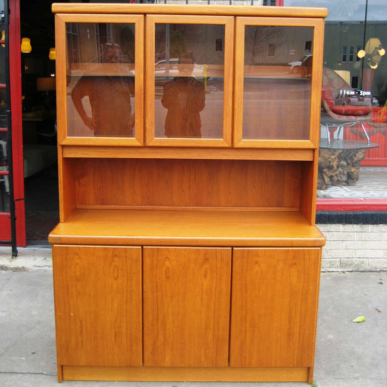 A beautiful Danish Modern buffet and hutch by Christian Linneberg. This piece is made of teak wood and comes with three functional hutch lamps. The hutch itself has three different glass-doored cabinets, while the bottom buffet section has three