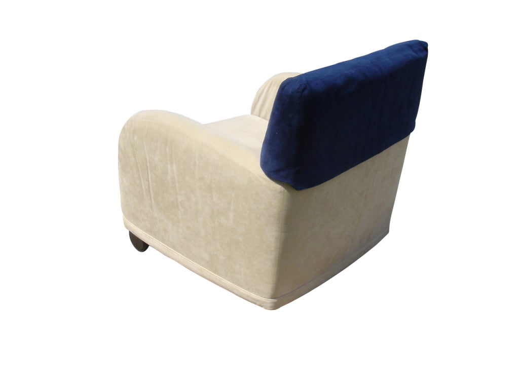 A postmodern Baisity lounge chair designed by Antonio Citterio and made by B&B Italia.  Plush beige upholstery with a removable blue headrest cover.  The front of the chair rests on casters.