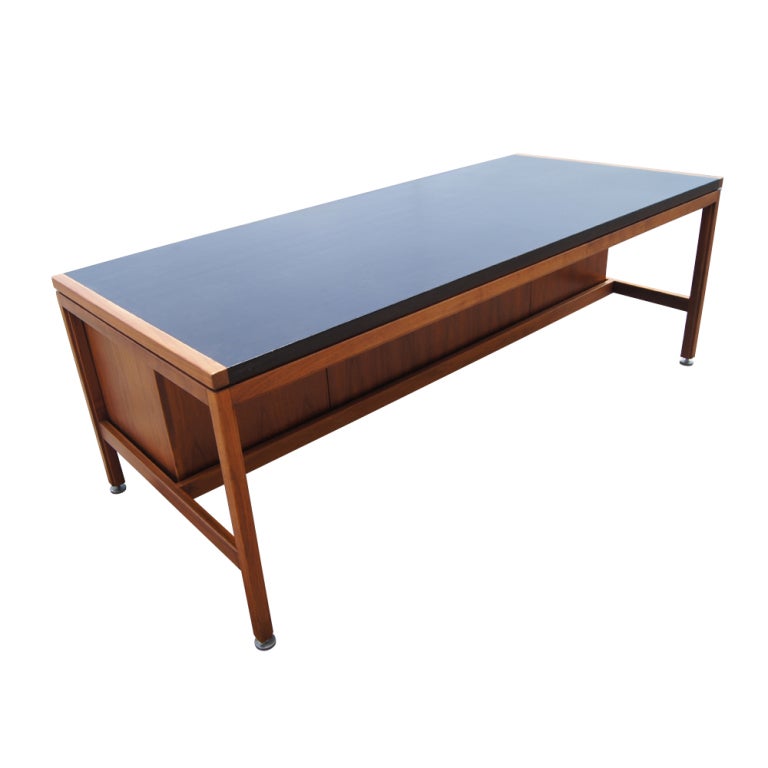 A mid century modern executive desk designed by Jens Risom and made by Jens Risom Design.  A walnut case with black leather top and five drawers and two pull-out writing surfaces.