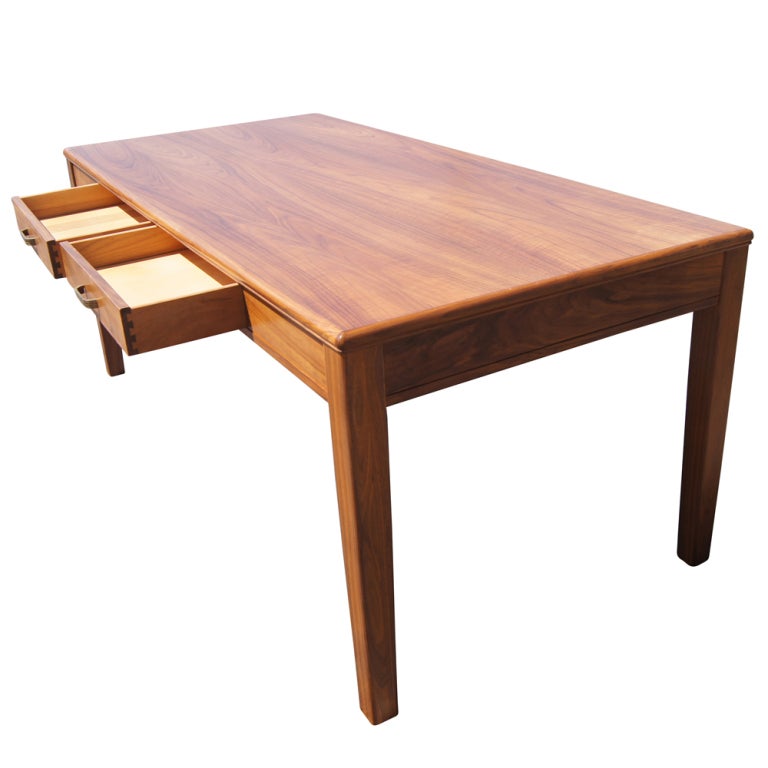A mid century modern walnut writing table or desk made by Lehigh Leopold with two drawers and brass hardware.
