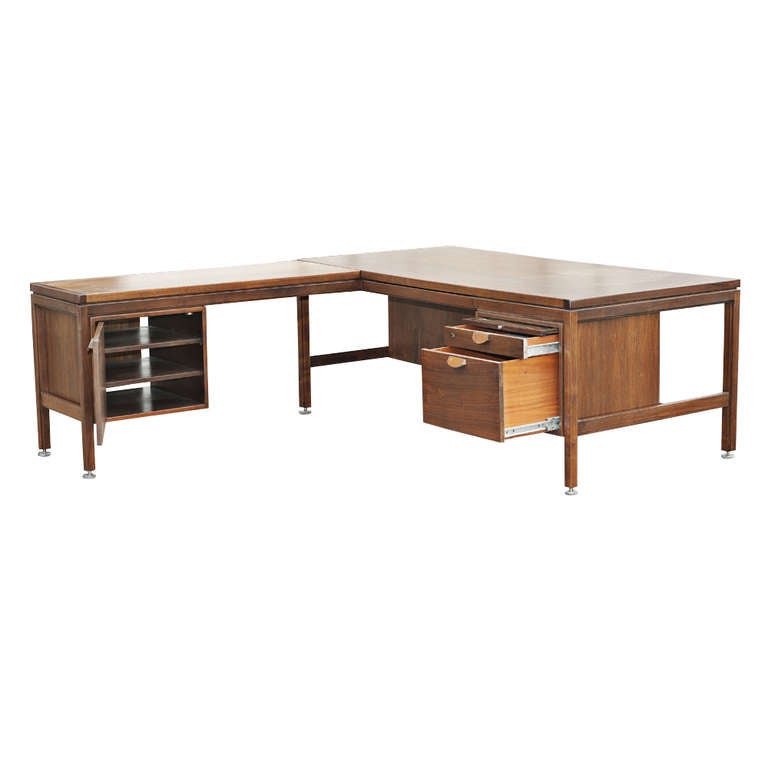 A walnut mid century modern L-shaped desk designed by Jens Risom and made by Jens Risom Design.  A classic desk with return is constructed of walnut. The desk features a pencil drawer, a standard drawer and file drawer on each side. The desk has
