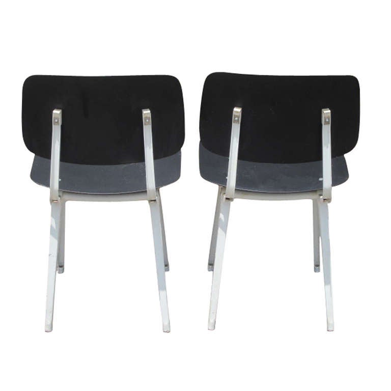A pair of vintage, industrial side chairs in the manner of Jean Prouve's classic Standard chair. 

Chairs feature steel legs with black composite seat and back.