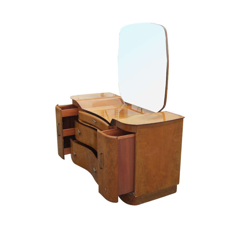 Un meuble-lavabo Art déco fabriqué par Beautility, avec un acajou magnifiquement grainé et un design élégant et fluide.  La commode comprend un miroir, deux grands tiroirs, un tiroir à bijoux et deux compartiments de rangement latéraux extractibles.