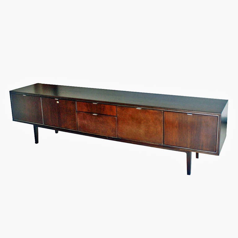 A breath taking walnut credenza by Stow Davis. Credenza features one file drawers, two regular standard drawers, one opposing cabinet doors with interior shelves, and chrome handle pulls. Wood trim and solid wood legs are also part of the