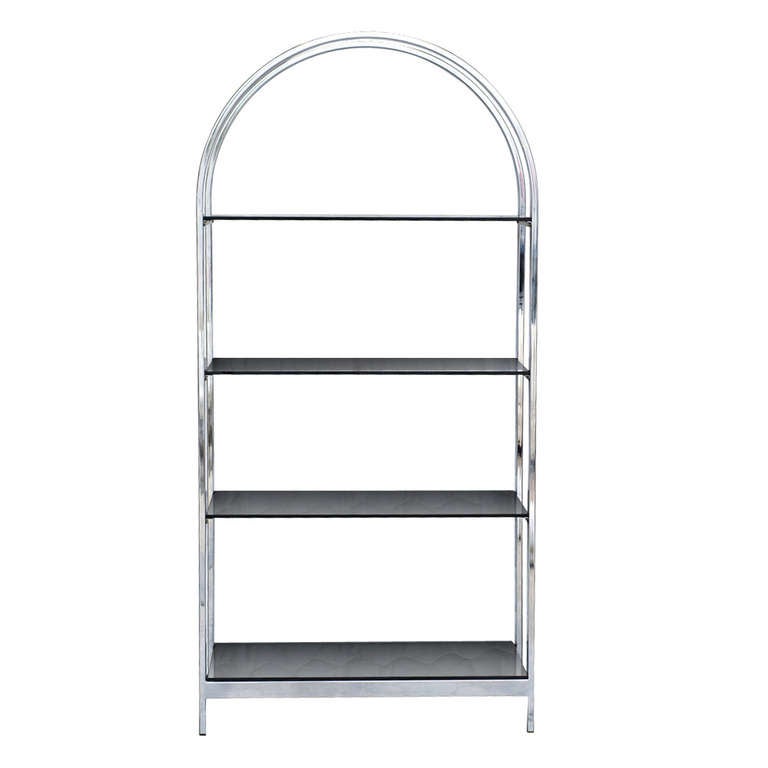 An elegant chrome etagere in the style of Milo Baughman. The arched chrome frame is equipped with four smoked glass shelves.
