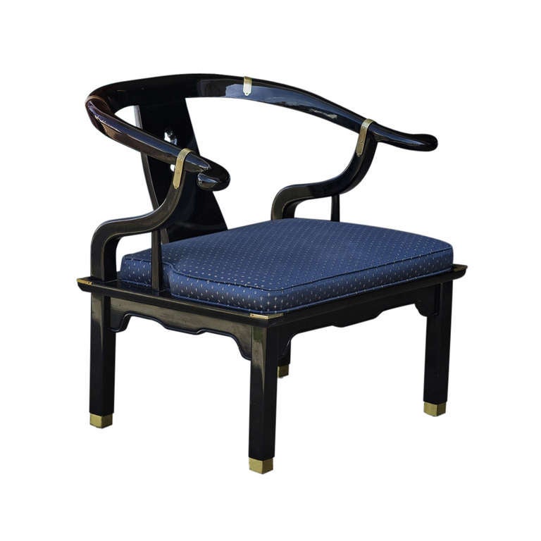 A pair of Chinoiserie style chairs in the manner of James Mont.  The chairs feature heavy black lacquered frames wirh brass accents and silk upholstery.