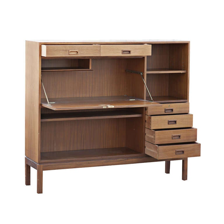 A multi-functional Danish style teak secretary/desk.  This secretary features a drop front desk and six drawers with distinctive recessed wooden drawer pulls.  There is also open shelving with adjustable shelves.  The back is finished.