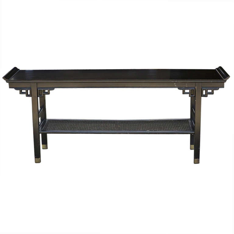 A beautiful Asian inspired pagoda style, black lacquer console table in the manner of James Mont.  

Center shelf features two cane inserts.  Legs are brass capped.
Beautiful Asian inspired pagoda style black lacquer console table.
