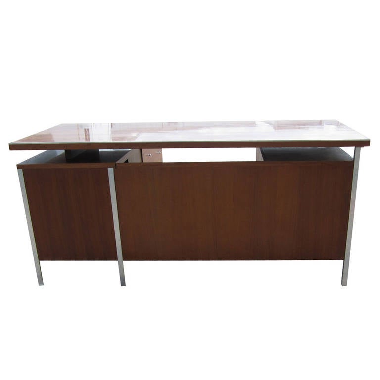 A Paul McCobb Connoisseur Collection reception desk for H. Sacks & Sons. This is a single pedestal, reception desk with a right hand return. A modesty panel, metal frame support and trimming is also featured along with 9 drawers and a writing