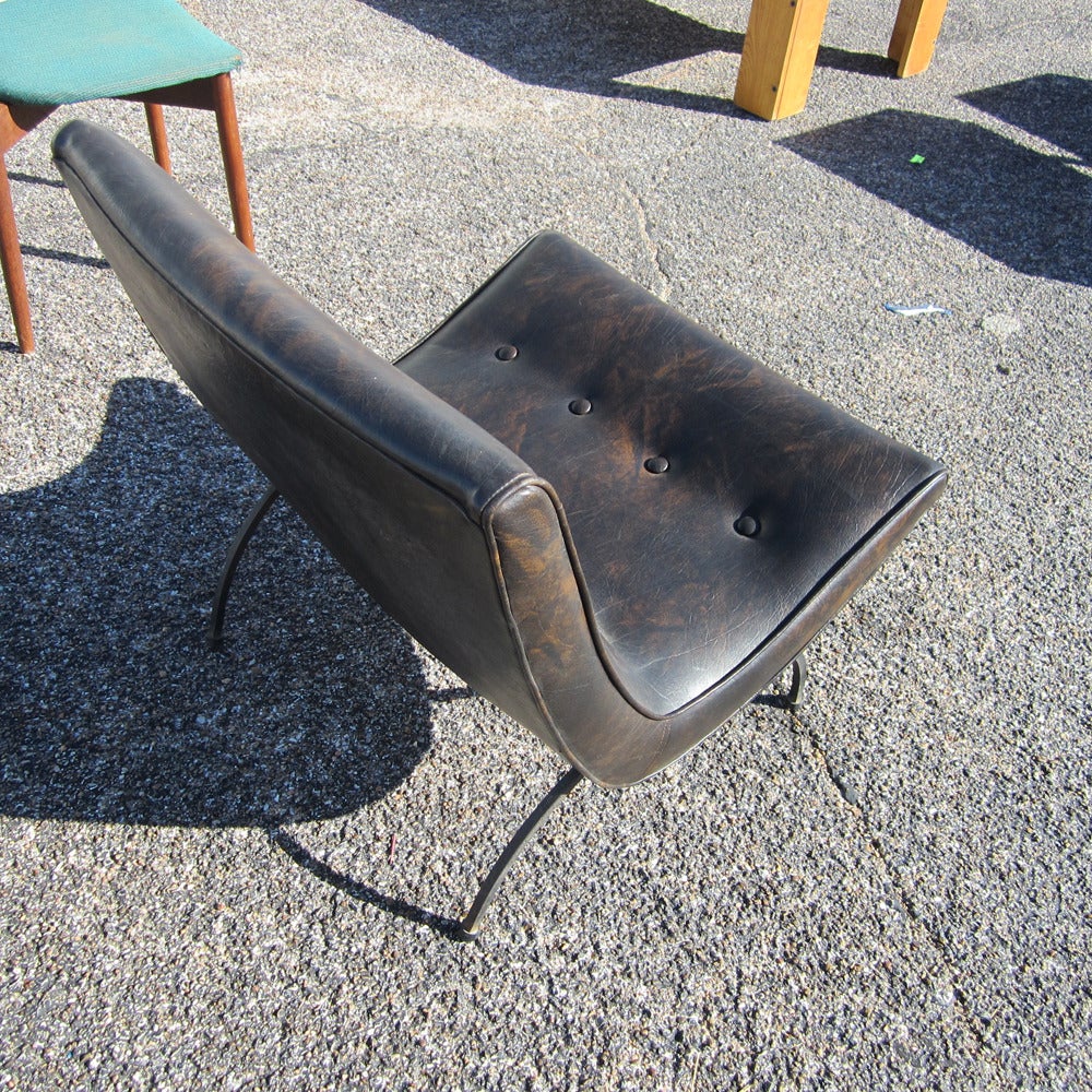 A vintage Mid Century Modern scoop chair by Milo Baughman. Comes upholstered in dark brown leather with a beautiful patina. Firmly tufted and well-cushioned. Four bent iron hemisphere legs, angled so as to give a decidedly relaxed posture to the