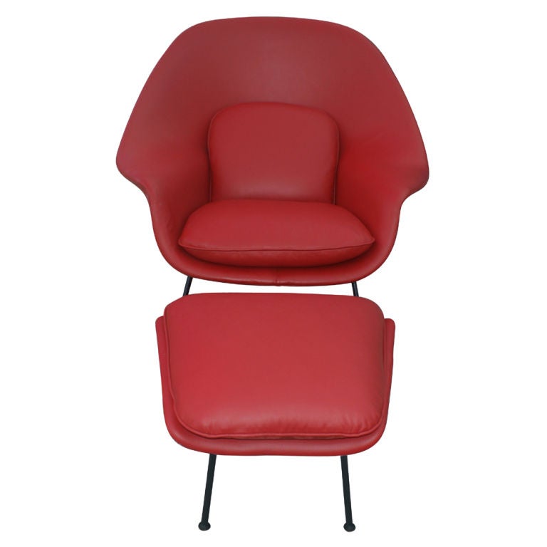 A mid century modern Womb chair and ottoman designed by Eero Saarinen and made by Knoll.  This is a vintage chair and ottoman with a black frame newly upholstered in red leather.  The ottoman's dimensions are 16