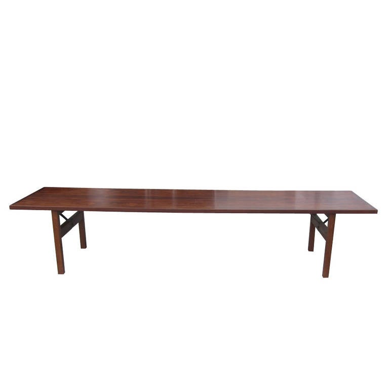 A vintage Mid-Century 6.5 foot bench made of rosewood. This bench has a Minimalist design that emphasizes the natural grain of the wood. A lovely bench that could also serve as a long coffee table.