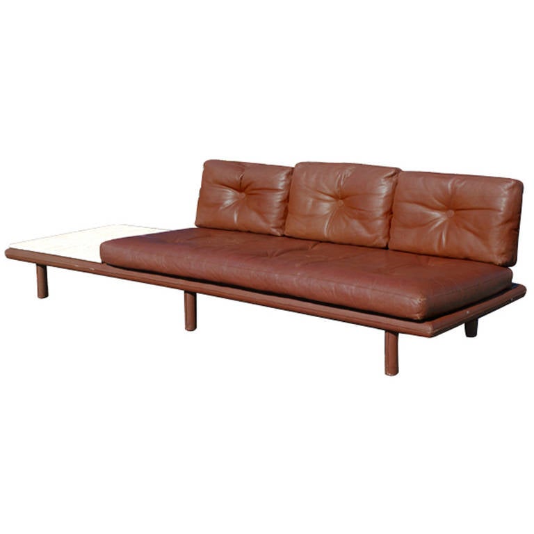 Unusual variation of the standard production, leather-covered wood frames over tapered teak legs, floating rectangular backrests with ebonized finish supported by steel rods, insert travertine marble table surface to sofa. Reupholstery