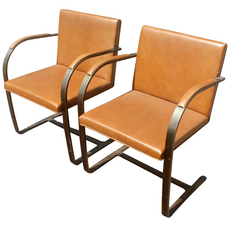 A pair of mid century modern Brno chairs designed by Mies van der Rohe and made by Knoll.  Unusual flatbar bronze frames with caramel brown leather upholstery.