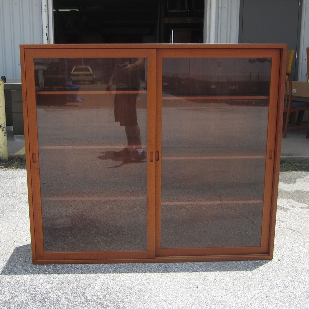 A vintage Mid-Century teak display cabinet featuring sliding glass doors and a Minimalist design, this piece is solid and practical. This iconic Swedish cabinet can make a great bookcase or China hutch.