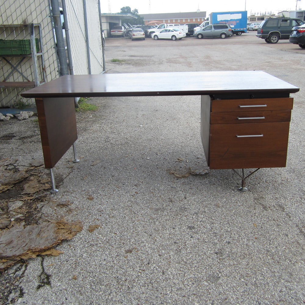 This piece has three drawers, one of which is a filing drawer. A very distinctive desk with unique capped off point stainless steel legs.