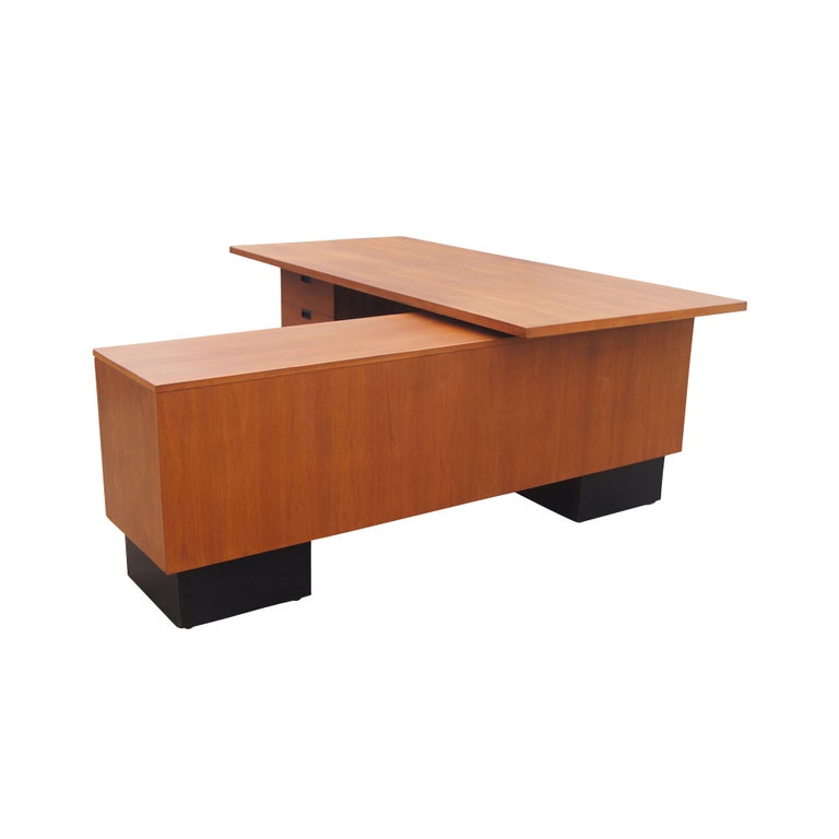 A mid century modern desk designed by George Nelson and made by Herman Miller.  Walnut construction with a right hand return all on black plinth supports.  The desk measures 83