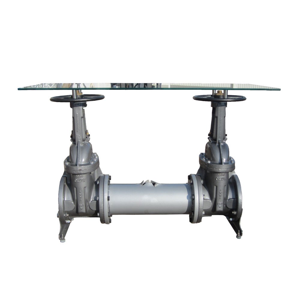 A re-purposed table made out of old Industrial water valve parts with a glass top. The handwheel and stem of the parts still turn and can turned to slightly adjust the height.
The pipe connecting the two valves has been expertly shredded to imitate