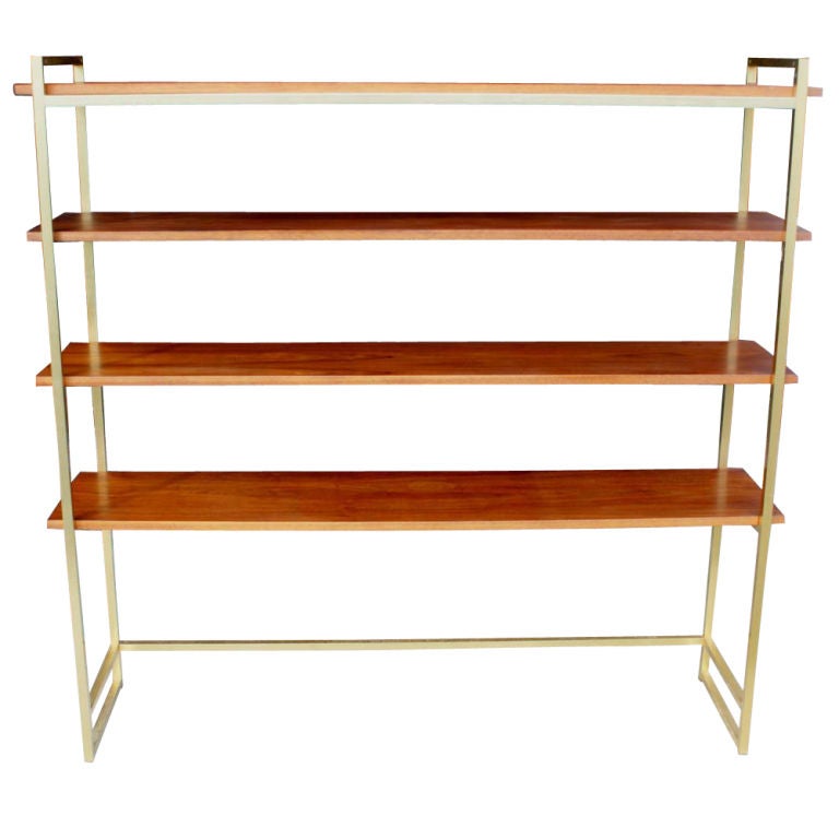 A midcentury modern shelving unit designed by Harvey Probber and made by his company.  Anodized brass frame with four walnut shelves.