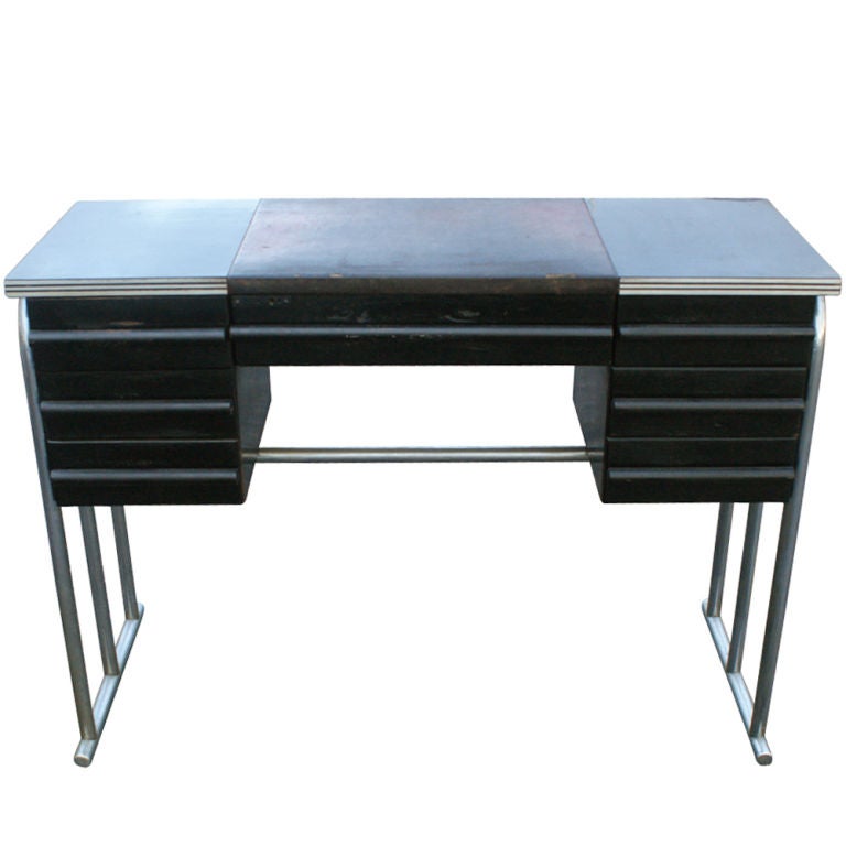 A Machine Age Art Deco desk and chair designed by Gilbert Rohde and made by the Troy Sunshade Company.  Aluminum frame supporting a wooden case with Bakelite top and leather writing surface.  Chair with tubular chrome base and vinyl upholstery.  The