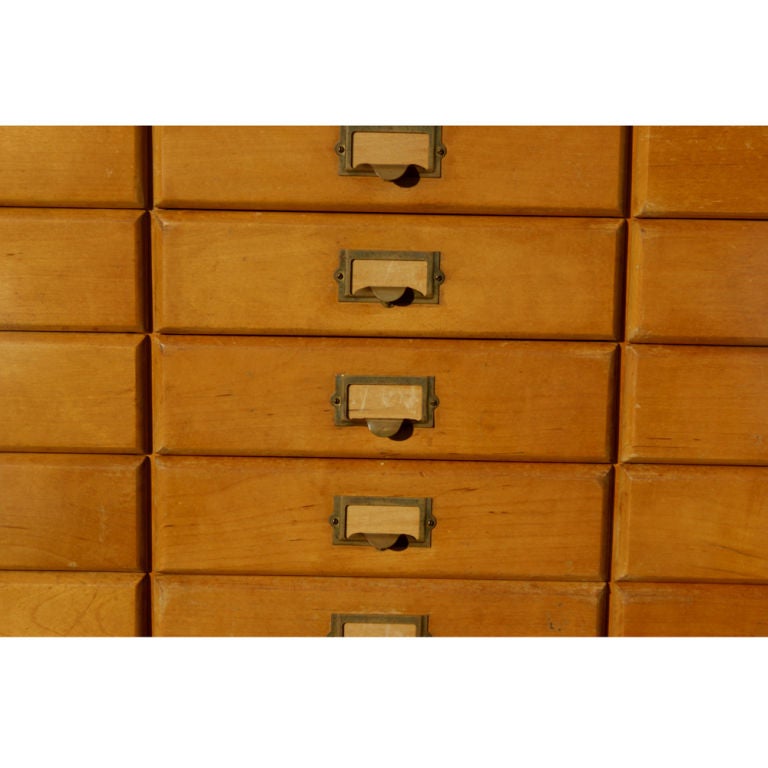 An oak cabinet with fifty-two slide out trays originally used for mail distribution.  Each drawer with a brass pull and space for an insertable label.  The drawers measure 9.75
