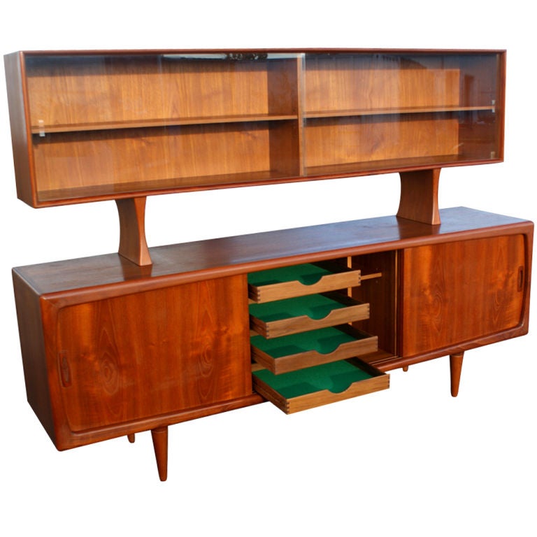 A mid century modern china cabinet and buffet made by H.P. Hansen of Denmark.  The teak buffet with three sliding doors.  Two doors concealing shelved storage and the center compartment with four felt lined drawers.  The teak china cabinet with two