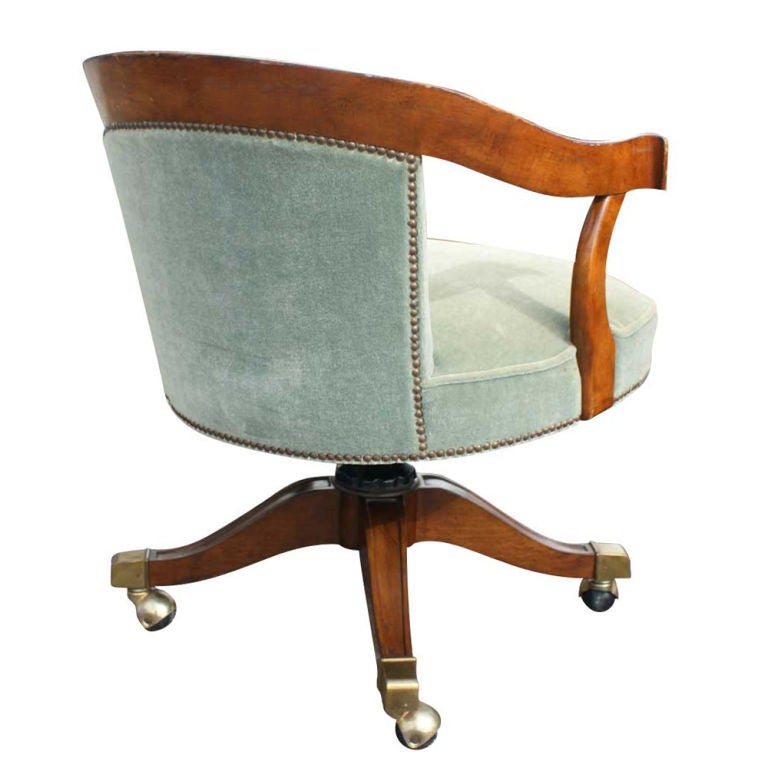 An office chair made by Baker with walnut frame and mint green velvet upholstery and decorative mailheads.  Four-star wooden base with brass caps and casters.  Seat height adjustable from 16