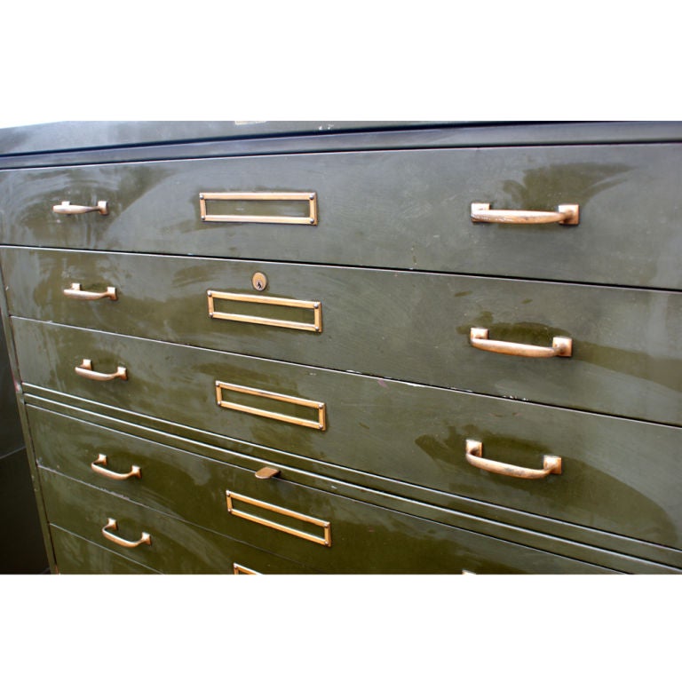 A  large, industrial file cabinet made by Corry Jamestown. Olive drab painted steel with brass hardware. A base, three sections with three drawers each, and a top. Each drawer measures 44.74