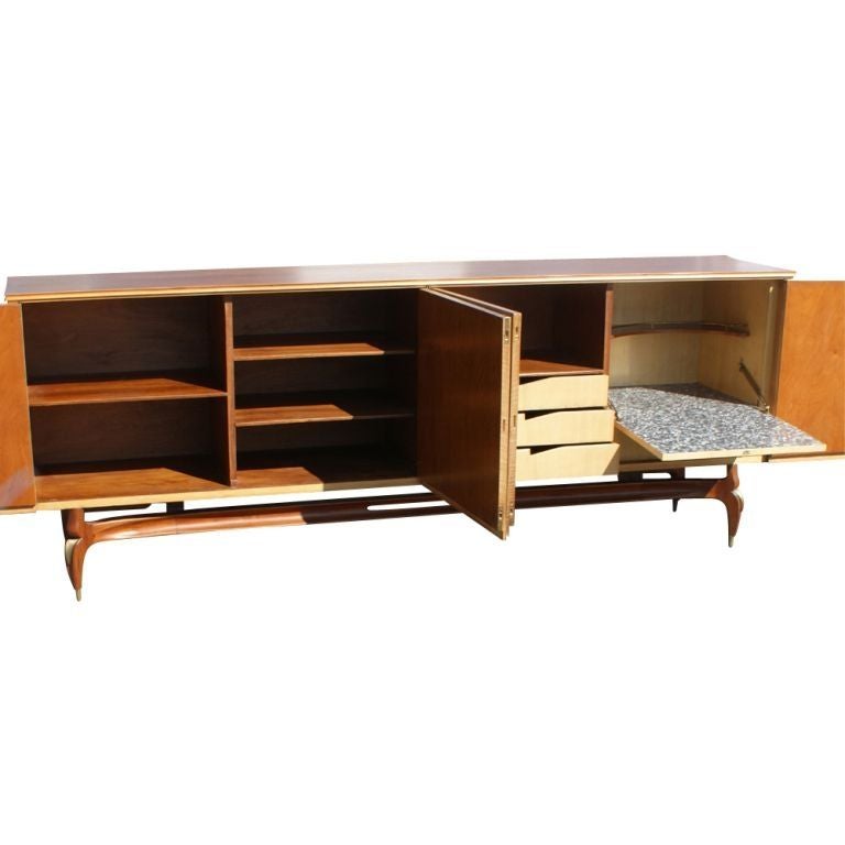 A mid century modern buffet or sideboard of Italian design.  The interior with extensive shelving, drawers and a drop front bar.  Walnut with brass detailing on the legs.  As shown in the last image, we also have a matching extension dining table on