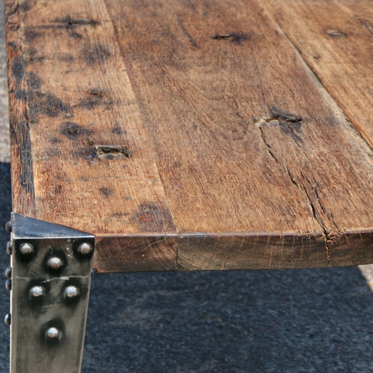 A long Industrial table made in France perhaps around the turn of the 20th cenury. Heavy riveted steel legs with a distressed plank top. Could be used as a large dining or conference table.  