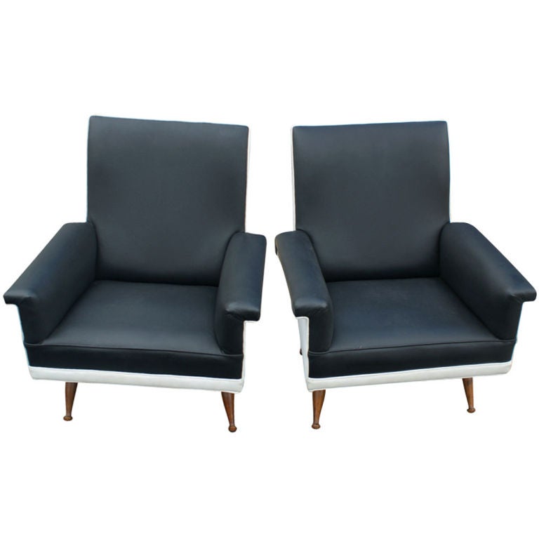 A pair of mid century modern Italian lounge chairs.  Black and white vinyl upholstery with angled wooden legs.