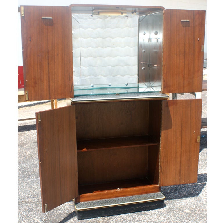 An Art Deco two section bar cabinet.  The upper, lighted part with mirrored interior, glass shelves, and laminate mixing surface.  The lower part with shelved storage.