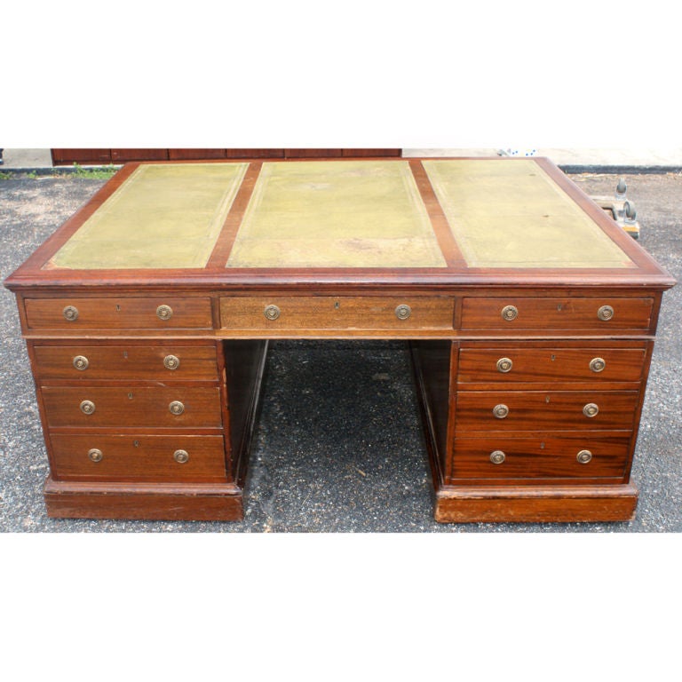 A fine traditional vintage double pedestal partner's desk in solid wood construction, with olive green leather top.