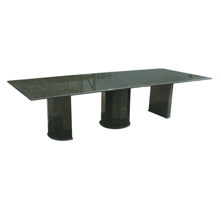A modern conference table ten feet long composed entirely of greenish/black granite.  A base consisting of three pedetals with a 3/4" top.