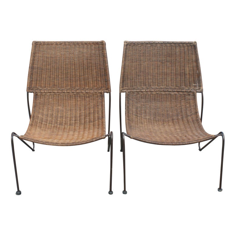 A pair of mid century modern lounge chairs designed by Frederick Weinberg.  Wicker seats and backs with wrought iron frames.