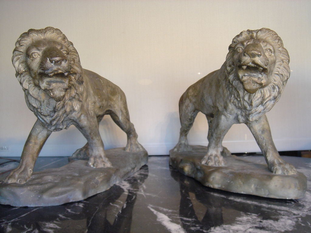 Two well modeled sculptures of a lion and lioness cast in a bronze or brass alloy. The striding subjects on bases with nicely detailed manes and faces. Possibly from the early 20th century.