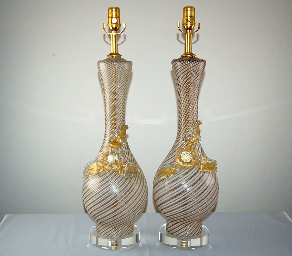 Glass flower petals adorn this elegant pair of Dino Martens lamps with filigrana of GOLD and WHITE. The petal of each flower is clear glass, filled with gold.

They Stand 27 inches from tabletop to socket top. As shown, the top of shade is 32