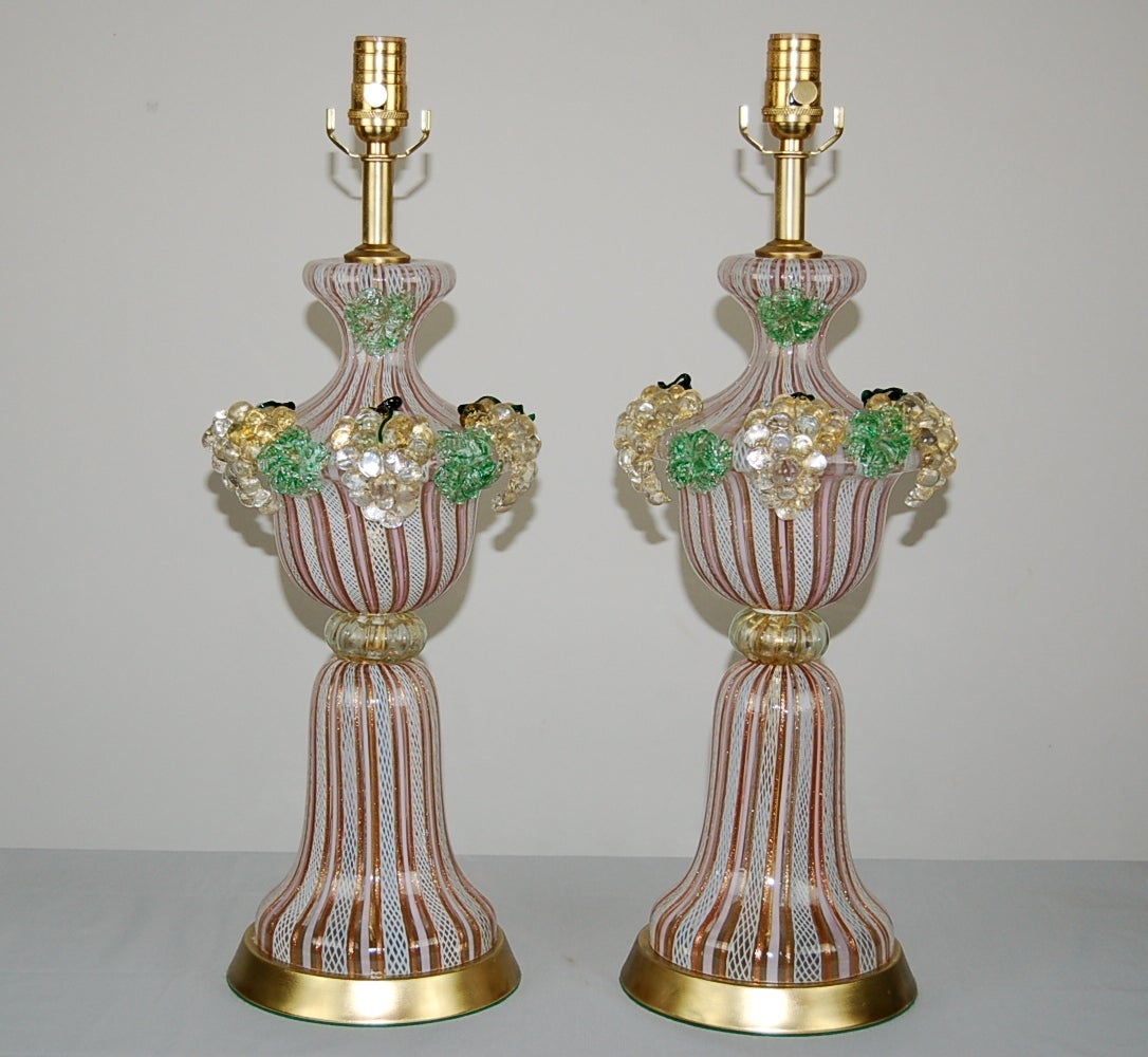 From our Carmen Miranda collection, intricately blown Murano lamps by Dino Martens. The fruit spilling over the top is beautifully detailed, and in perfect condition. Striped lamp bodies of PINK, COPPER, and WHITE are joined together by a GOLD