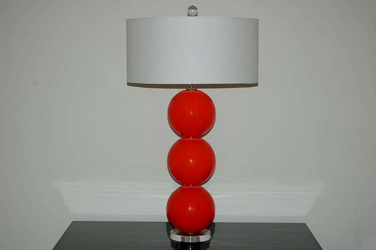 Matched pair of handblown three-ball glass lamps by Joe Cariati in Vermillion. The Vertical ribs add optics and teture. 

They stand 28 inches to the top of the socket, (the glass pieces alone total 22 inches). As shown, the top of shade is 34