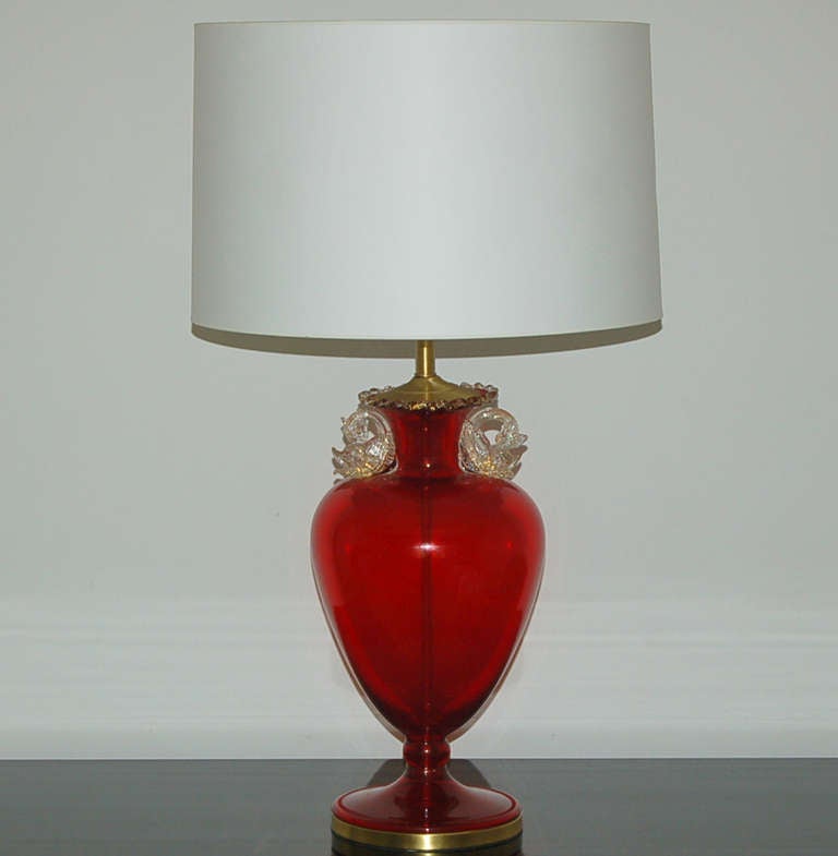 This pair of lamps is so rare; we have never seen a pair available before now. The urn-shaped glass is a deep ruby red. The handles are dolphins fashioned of gold dusted clear Murano glass with gems for eyes. 

The lamps are 29 inches to the top